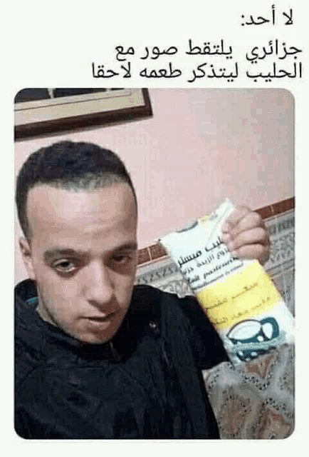 a man is holding a bottle of milk and taking a selfie .