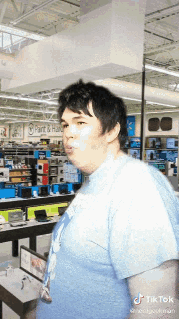 a man in a blue shirt is standing in front of a sign for paint & hardware