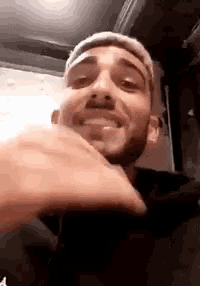 a man with a beard is smiling and making a funny face while looking at the camera .