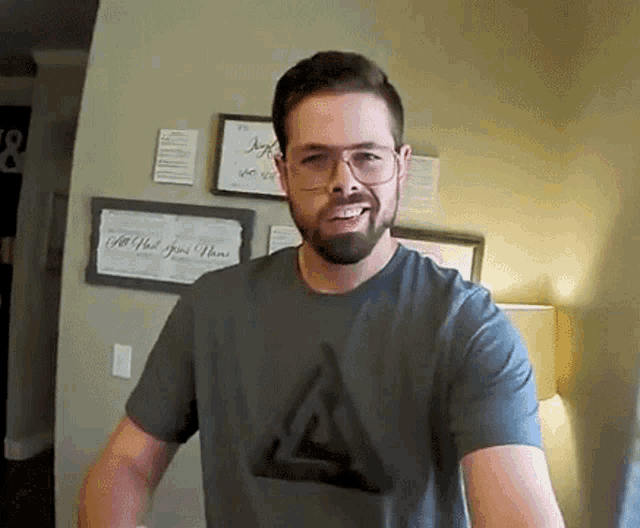 a man with a beard wearing glasses and a t-shirt with a triangle on it