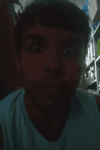 a man wearing a blue tank top making a funny face