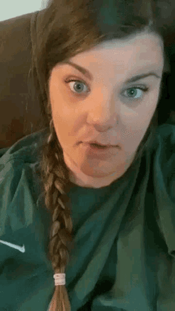a woman with a braid is wearing a green nike sweatshirt .