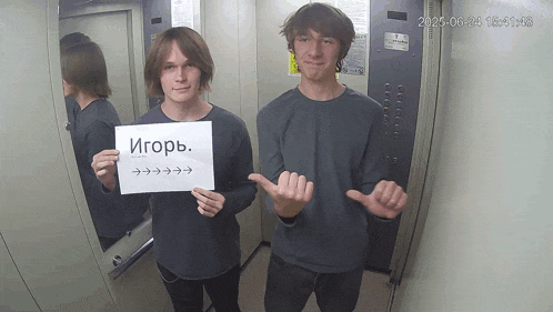 two young men in an elevator holding a sign that says igorb