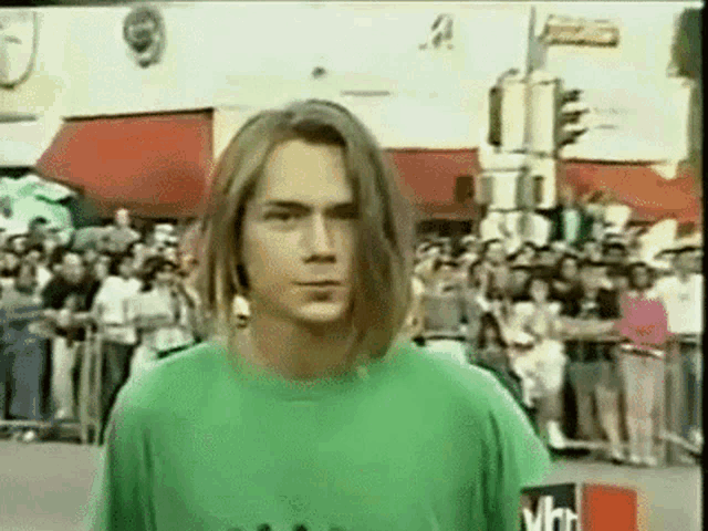 a young man in a green shirt is standing in front of a crowd .