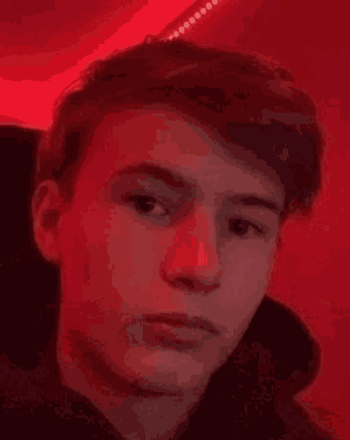 a close up of a young man 's face with a red background .