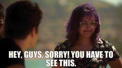 a woman with purple hair is talking to a man with glasses .