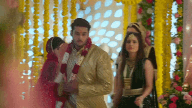 a bride and groom are standing next to each other in a room with flowers .