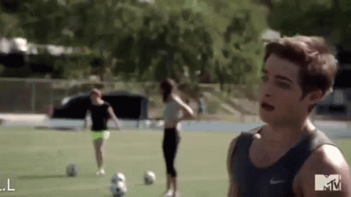 a man and a woman are playing soccer on a field with a mtv logo in the background