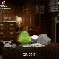 a green monster is sitting on top of a desk in a room .