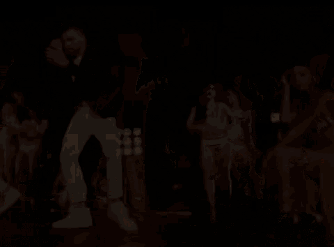 a group of women in bikinis are watching a man in a suit dance