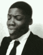 a black and white photo of a man wearing a suit and tie .
