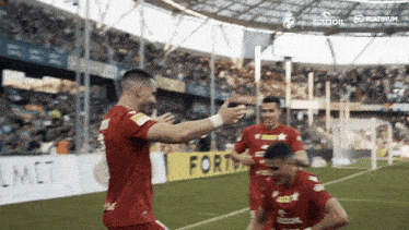 a group of soccer players are celebrating a goal in front of a banner that says fortuna