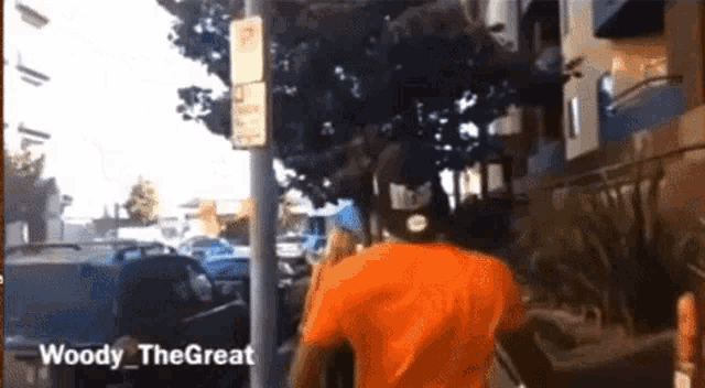 a man in an orange shirt is walking down a street with the words woody the great written on the bottom