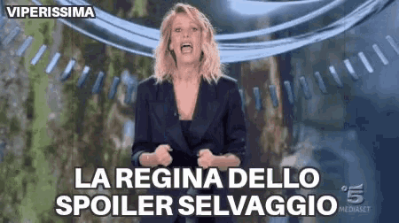 a woman in a suit is standing in front of a banner that says la regina dello spoiler selvaggio .
