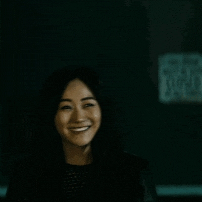 a woman is smiling in the dark in front of a sign that says ' a ' on it .