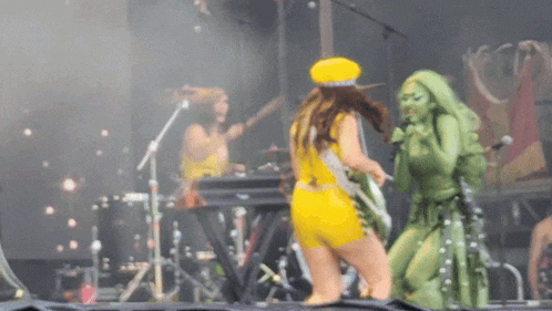 a woman in a yellow outfit is dancing on stage