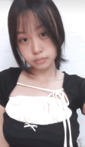 a young girl wearing a black top with a white bow on the front