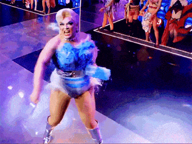 a drag queen in a blue and white outfit is dancing on stage