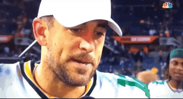 a man with a beard wearing a white hat and a green jersey