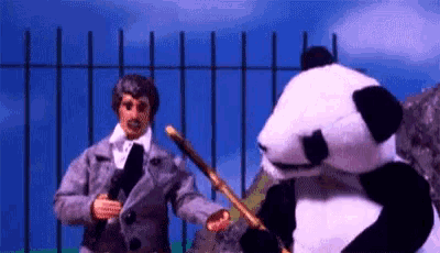 a man in a suit and tie is standing next to a panda bear holding a cane .