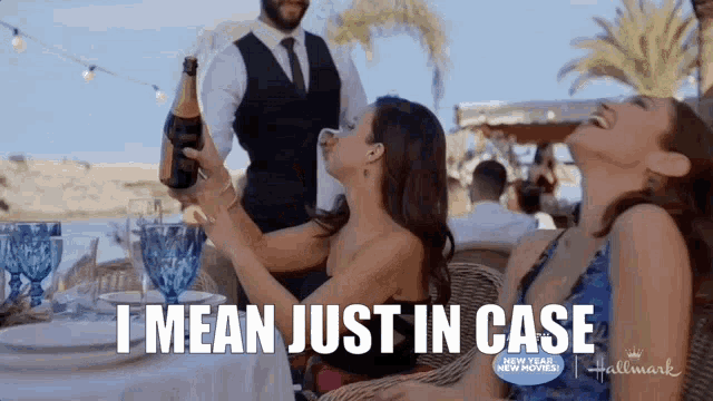 two women are sitting at a table with a man holding a bottle of champagne and the words i mean just in case above them .