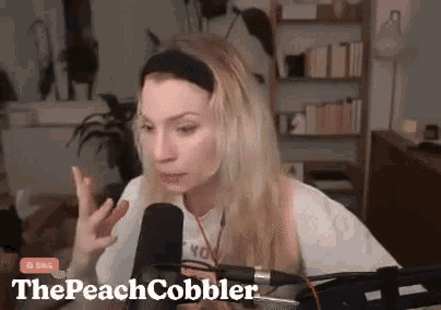 a woman is talking into a microphone in front of a bookshelf .
