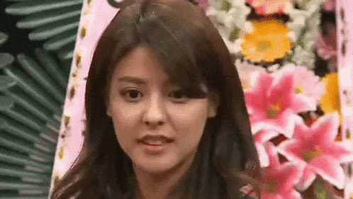 a woman is standing in front of a bouquet of flowers and making a funny face .