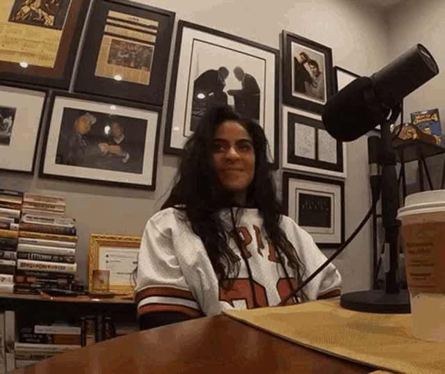 a woman sitting in front of a microphone wearing a jersey that says pi