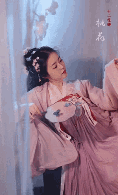 a woman in a purple dress is holding a fan with chinese writing on the bottom