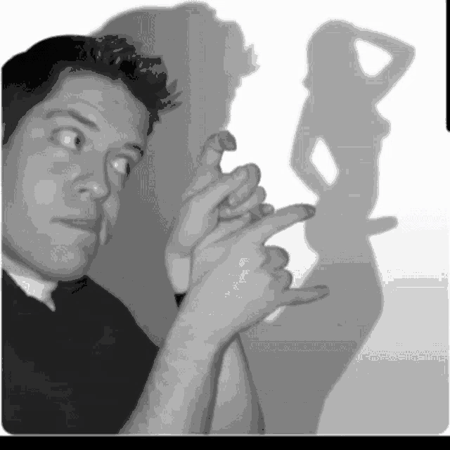 a black and white photo of a man making a hand gesture