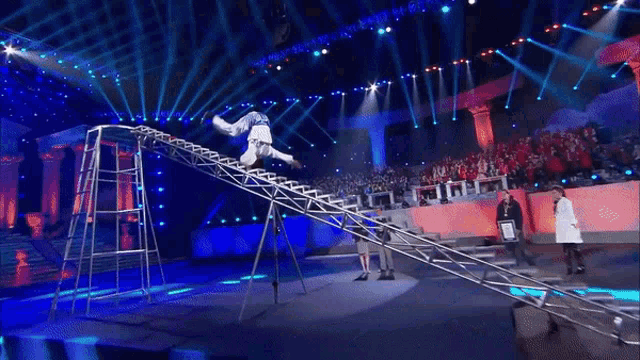 a man is doing a handstand on a ladder in front of a crowd