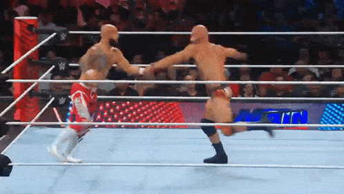 two men are wrestling in a ring and one of them is wearing shorts that say ' united states of america ' on them