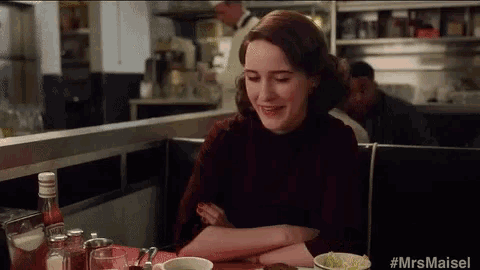a woman is sitting at a diner table with her arms crossed .
