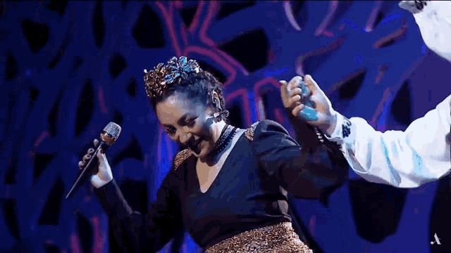 a woman is singing into a microphone while wearing a crown