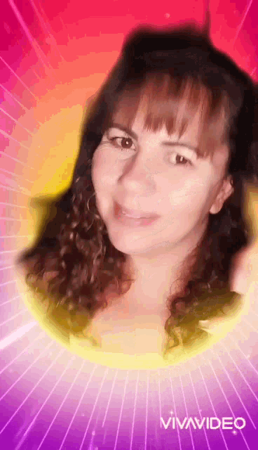 a woman with curly hair is smiling and looking at the camera on a pink and yellow background .