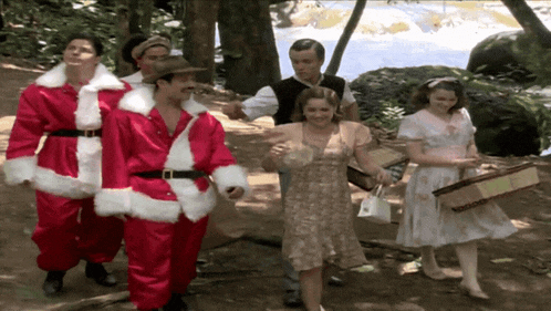a group of people dressed in santa costumes are walking in a forest