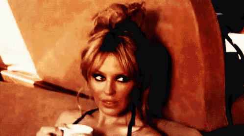 a woman is holding a cup of coffee and looking at the camera .