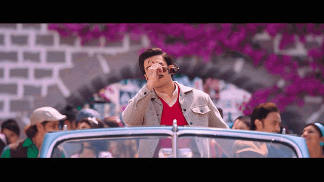 a man wearing sunglasses and a red shirt is in a car