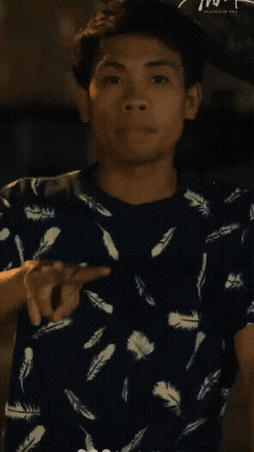 a young man wearing a shirt with feathers on it
