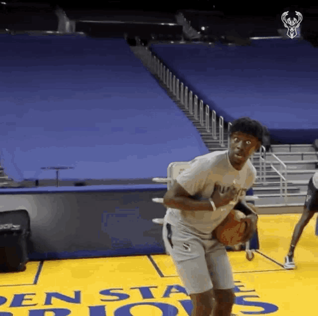 a man is holding a basketball on a basketball court that says penn state