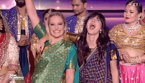 a group of women are posing for a picture and one of them is wearing a green sari