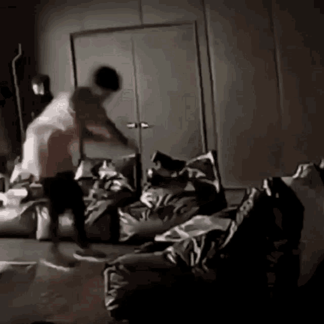 a person is standing on a bed in a dark room with a lot of pillows .