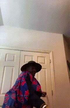 a man wearing a hat and a floral shirt is standing in a room
