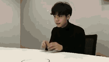 a young man is sitting at a table with a glass of water in front of him .