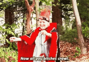 a woman in a red cape is standing in the woods and says " now all you bitches crawl "