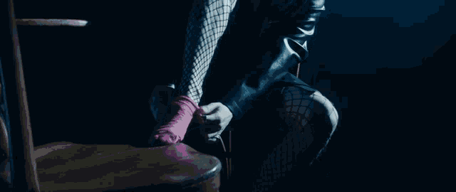 a woman in fishnet stockings and a leather jacket is holding a pink object