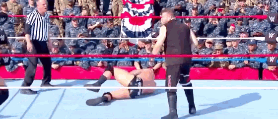 a referee is standing next to a wrestler in a ring .