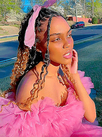 a woman in a pink dress is standing on the side of the road .