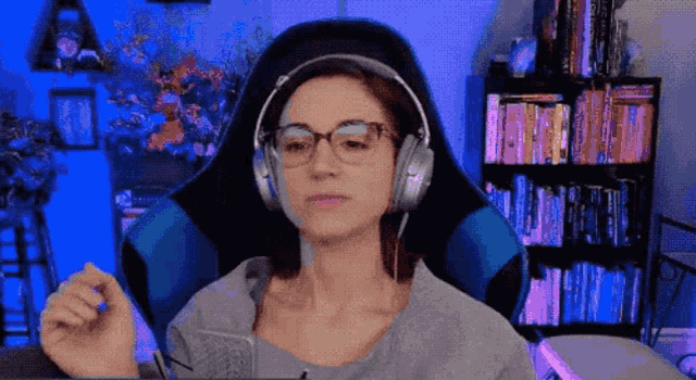 a woman wearing headphones and glasses is sitting in a chair