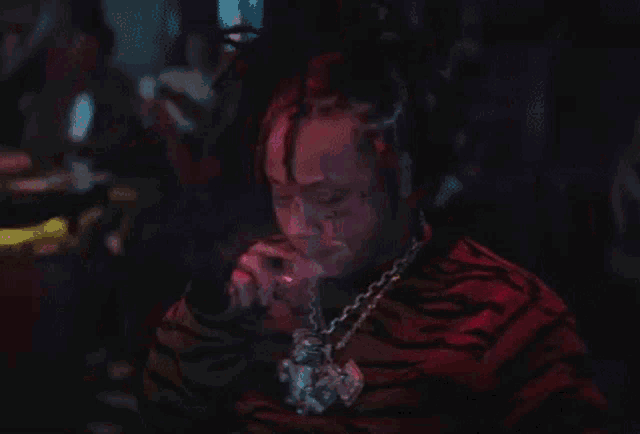 a man with dreadlocks is smoking a cigarette in a dark room .